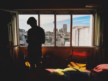 Rear view of silhouette man standing in glass window