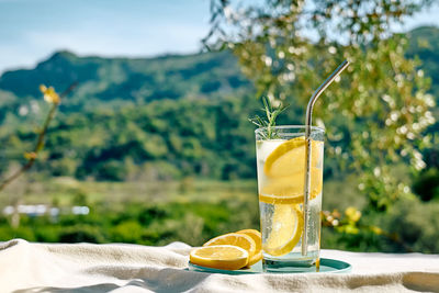 Summer refreshing lemonade drink or alcoholic cocktail with ice, rosemary and lemon slices on table