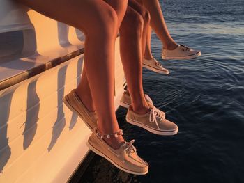 Low section of women sitting at boat over sea