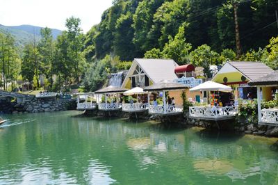 Houses by river against buildings