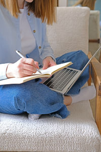 Midsection of woman using digital tablet while sitting at home