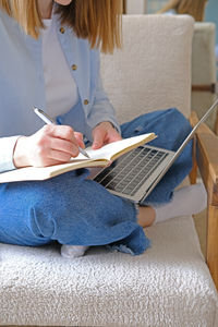 Midsection of woman using digital tablet while sitting at home