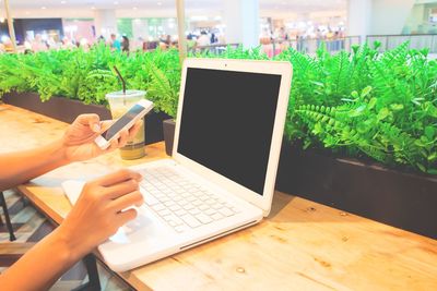 Midsection of person using mobile phone at table