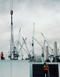 Cranes at construction site against sky