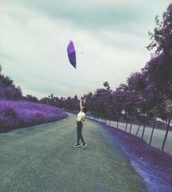 Full length rear view of woman walking against purple sky