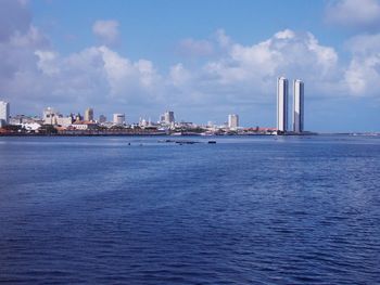 Sea by buildings against sky