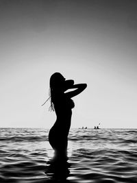 Silhouette woman standing in sea against clear sky