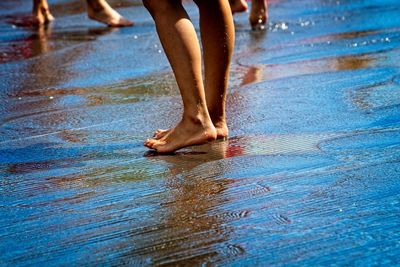 Low section of people standing on land with water