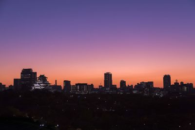 Silhouette buildings in city against sky during sunset