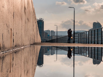 Reflection of buildings in city against sky