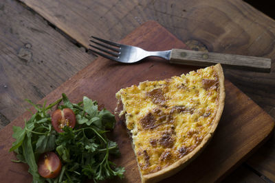 High angle view of savory pie slice with salad on wooden plate