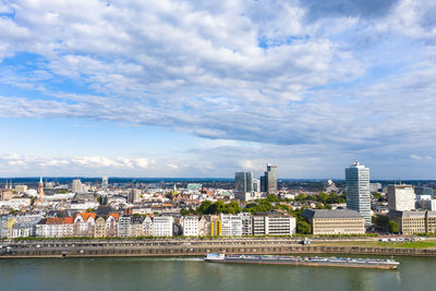 Buildings by river against sky in city
