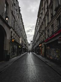 Empty road amidst buildings in city against sky