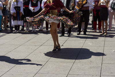 Low section of people in traditional clothing dancing on street in city