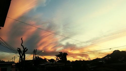 Low angle view of power lines against cloudy sky