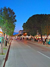 People on street in city against clear blue sky