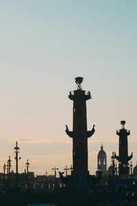 Silhouette of statue in city against sky during sunset