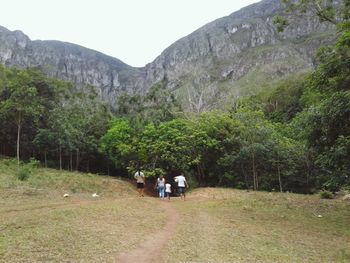 People walking on landscape against mountain