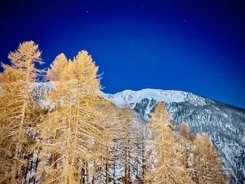 Low angle view of snowcapped mountain against blue sky