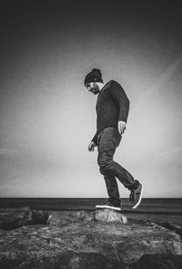 Side view of man on sea shore against sky