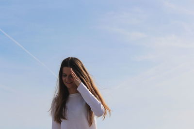 Portrait of smiling woman standing against sky