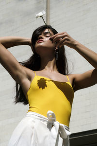 Midsection of woman holding yellow while standing outdoors