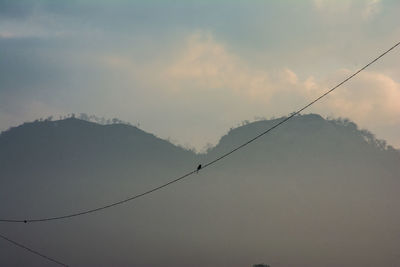 Low angle view of overhead cable car against sky