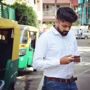 Man using mobile phone while standing on street in city