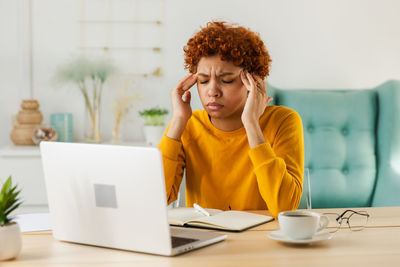 Young woman using laptop while sitting on table