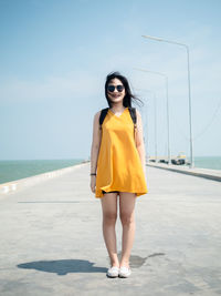 Young woman wearing sunglasses while standing by sea