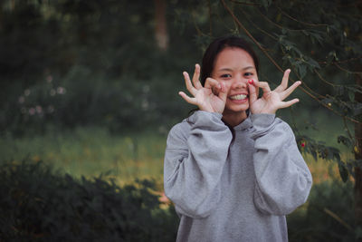 Portrait of smiling young woman with berry gesturing while standing on field