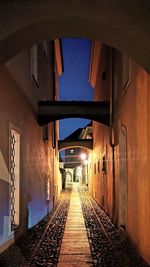 Empty alley amidst buildings in city at night