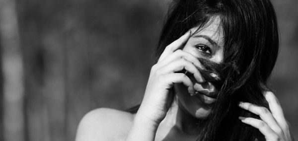 Close-up portrait of woman with hand on hair