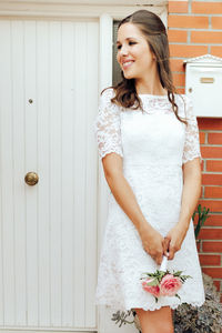 Portrait of smiling woman standing against wall