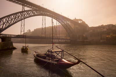 Boat on douro river by dom luis i bridge during sunrise in city