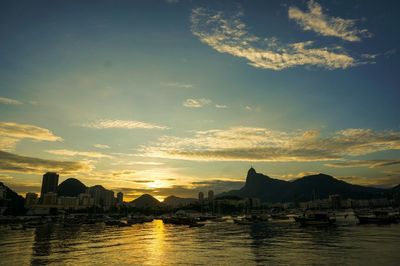Scenic view of river in front of town against sky during sunset