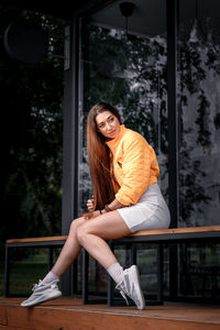 Portrait of young woman sitting on railing