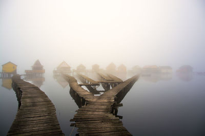 Pier over lake in foggy weather