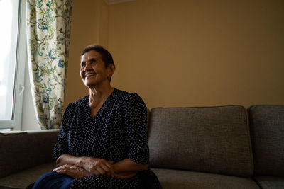 Portrait of smiling senior woman in eyeglasses sitting at home