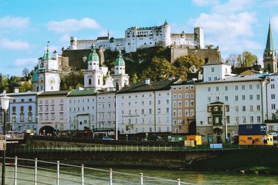 Buildings by river against sky in city