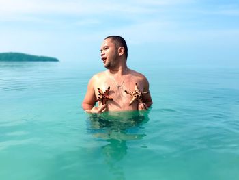 Young man in sea against sky