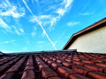 Low angle view of building roof against blue sky