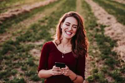 Portrait of smiling young woman using smart phone outdoors