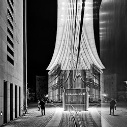 People walking on street amidst buildings in city at night