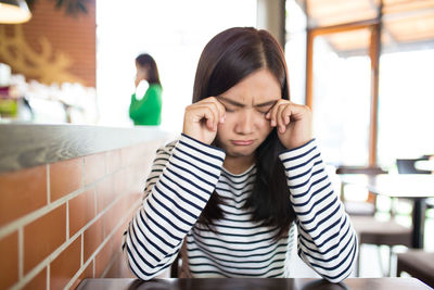 Young woman crying while sitting at restaurant