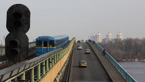 Vehicles on road against sky in city