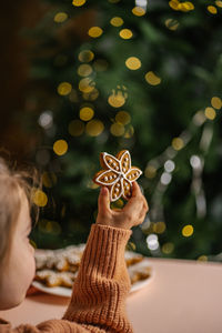 Ginger christmas cookies in children's hands on the background of the christmas tree.