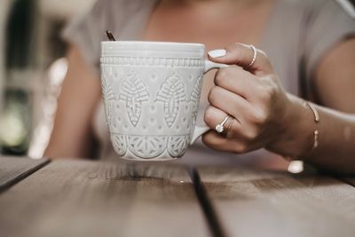 Midsection of woman holding coffee cup on table
