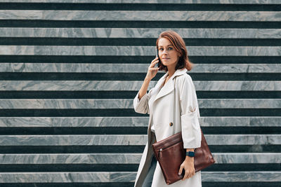 Portrait of young woman standing against wall