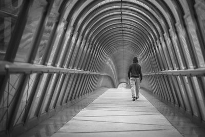 Rear view of man walking on covered walkway